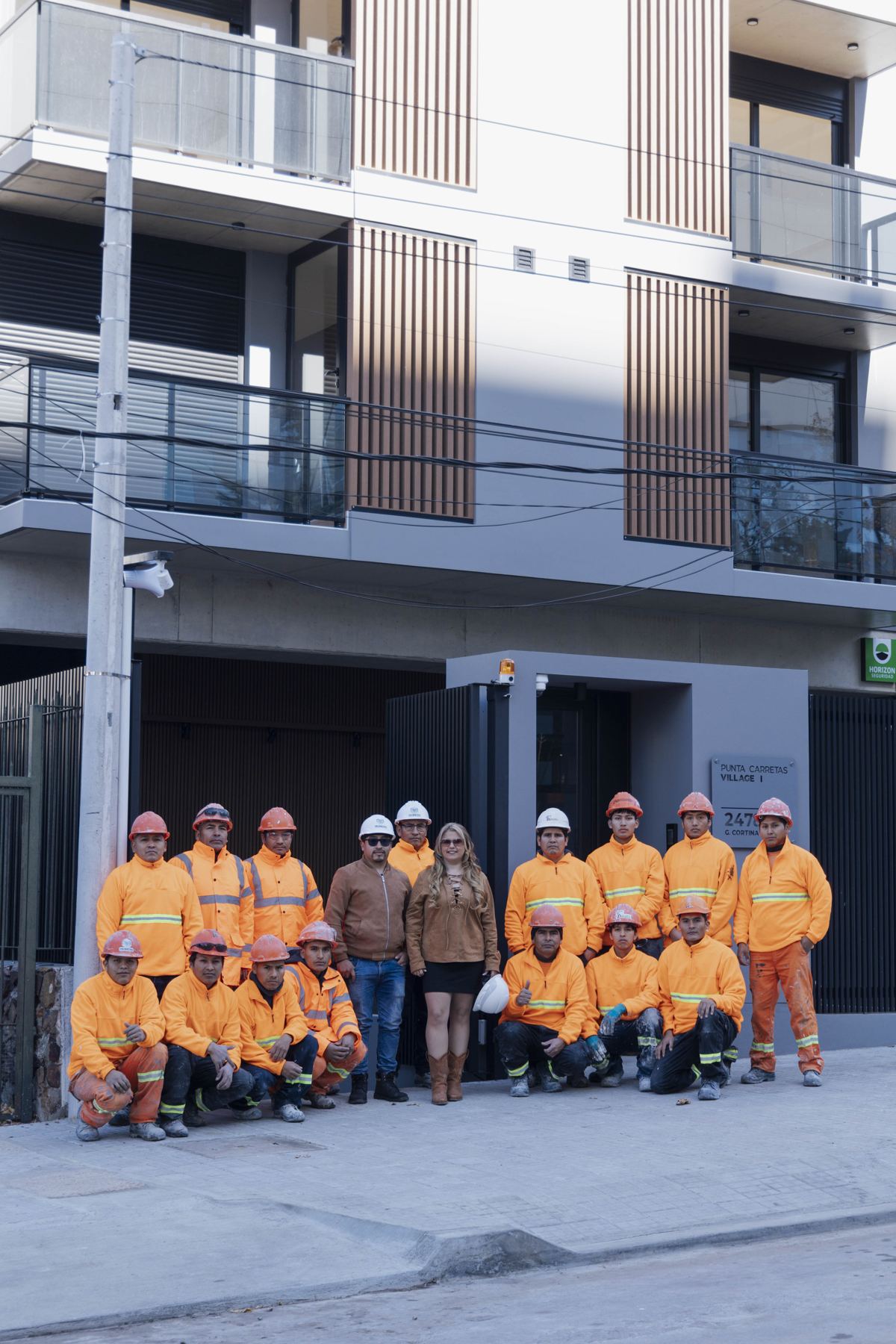 Equipo de Milímetro con uniformes naranjas frente al edificio terminado